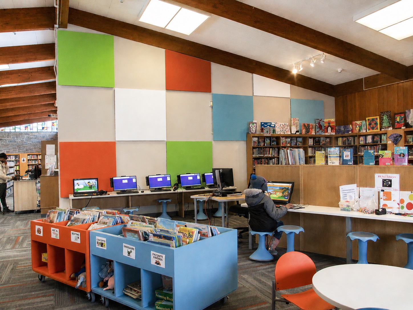 Children's library area with colorful wall panels, books, and computer stations