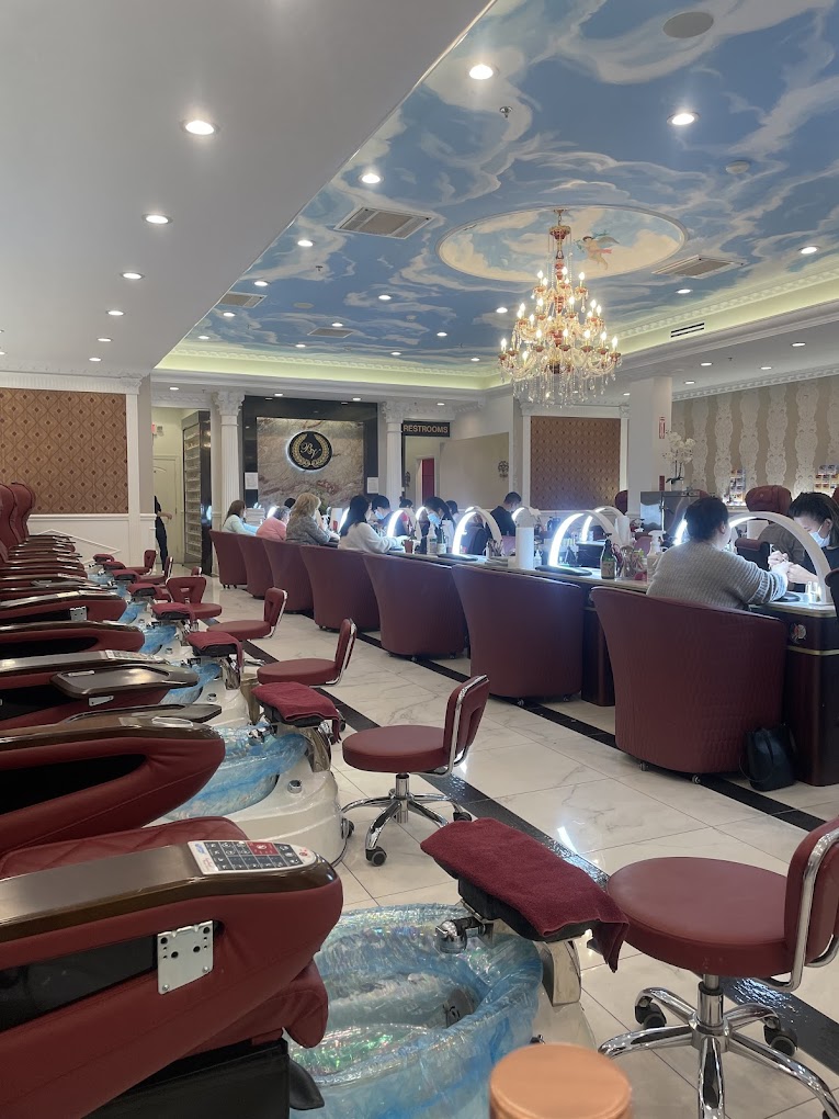 Elegant nail salon with burgundy chairs, manicure stations, and chandelier ceiling
